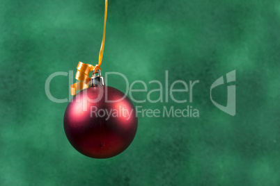 red christmas ball hanging with orange ribbon on green background