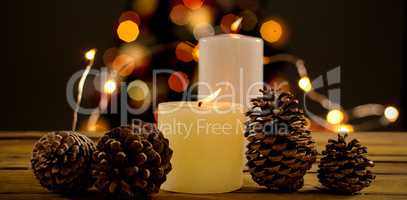 Composite image of close up of pine cones with illuminated candles on table