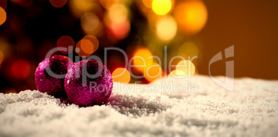 Composite image of christmas balls against unfocused tree