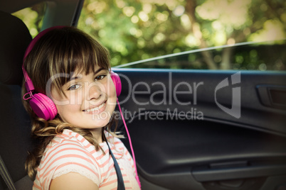 Smiling Teenage girl with headphones in the back seat of car