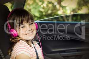 Smiling Teenage girl with headphones in the back seat of car