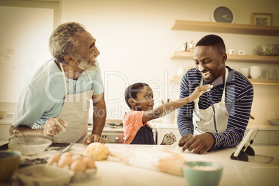 Multi-generation family with flour on the nose standing in the kitchen