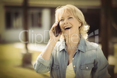 Senior woman talking on mobile phone outside his house