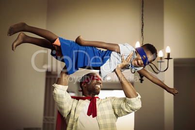 Playful father and son in superhero costume at home