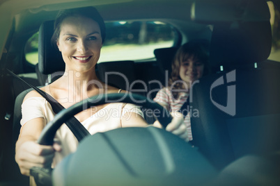 Woman driving a car while daughter sitting in the backseat of car