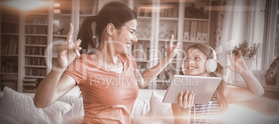 Happy mother and daughter using digital tablet and dancing