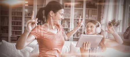 Happy mother and daughter using digital tablet and dancing