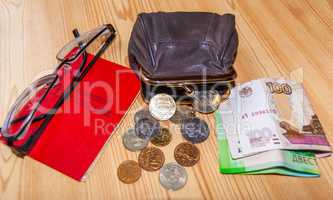 On the table are small bills and coins, an open purse and glasses next to the pensioner's certificate. Inscription: "Pension certificate"