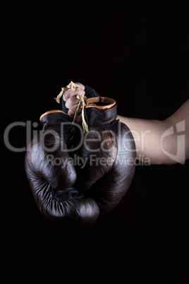 man's hand holds a pair of old leather brown boxing gloves