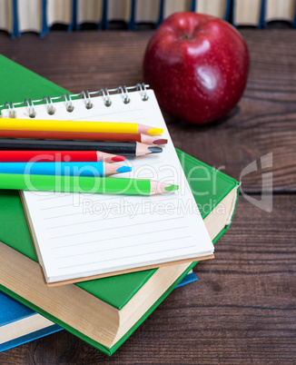 empty open notebook and multicolored wooden pencils