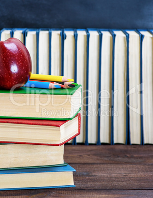 ripe red apple lying on a stack of books