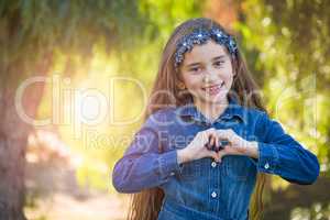 Cute Young Mixed Race Girl Making Heart Hand Sign Outdoors