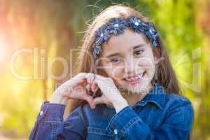 Cute Young Mixed Race Girl Making Heart Hand Sign Outdoors