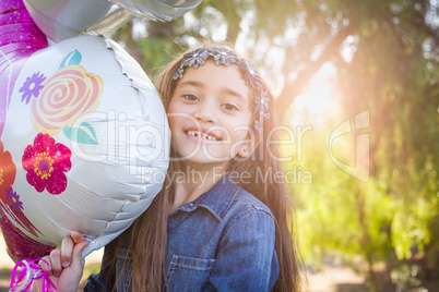 Cute Young Mixed Race Girl Holding Mylar Balloon Outdoors