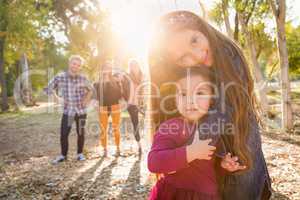 Mixed Race Young Girl Sisters Outdoors with Family Behind