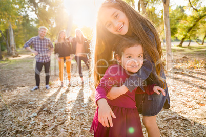 Mixed Race Young Girl Sisters Outdoors with Family Behind