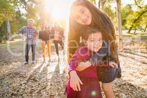 Mixed Race Young Girl Sisters Outdoors with Family Behind