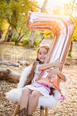 Cute Young Girl Playing With Number Seven Mylar Balloon Outdoors