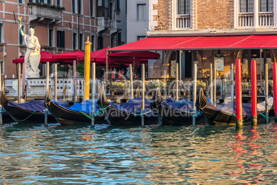 Gondolas near an italian street cafe in the Grand Canal of Venic