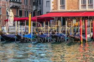 Gondolas near an italian street cafe in the Grand Canal of Venic