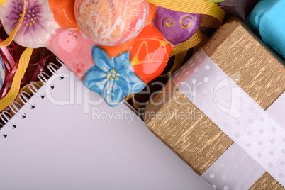Arrangement of Gift Boxes in Wrapping Paper with Checkered Ribbons and Decorated Easter Eggs. White paper notepad