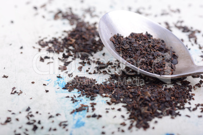 Black tea in a spoon on a white background. Close up shot