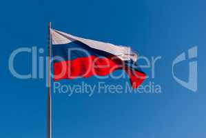 The national flag of Russia on the flagpole fluttering wind against the blue sky. Russia