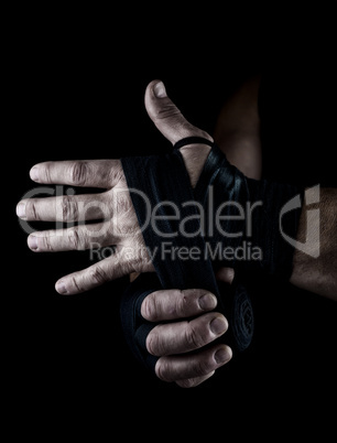 man wraps his hands in black textile bandage for sports
