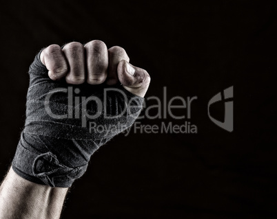lifted up fist of athlete wrapped in black textile bandage