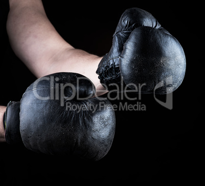 men's hands are wearing old leather black boxing gloves