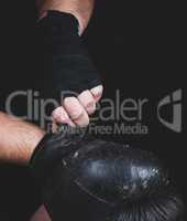 athlete puts on black leather boxing gloves