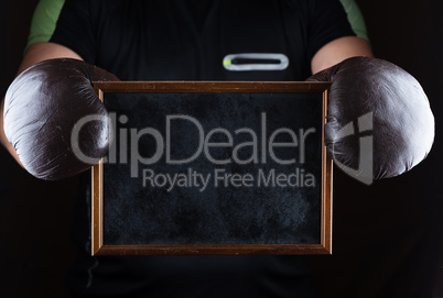 men's hands in boxing gloves hold an empty black frame