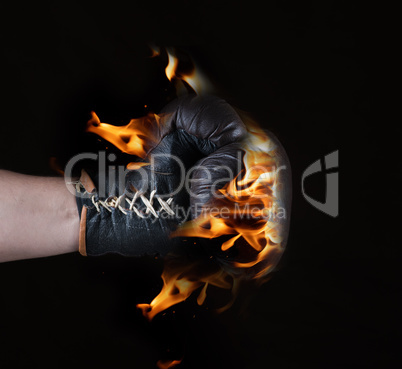 Brown leather glove in flames on a black background
