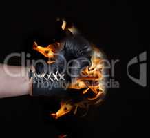 Brown leather glove in flames on a black background