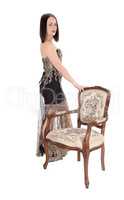 Lovely woman standing with old armchair in dress