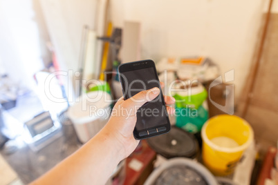 Hand holds a mobile phone on a construction side