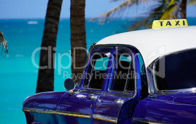 Oldtimer taxi in front of palms at the sea