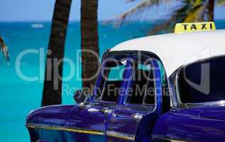 Oldtimer taxi in front of palms at the sea