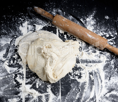 white wheat flour dough and wooden rolling pin