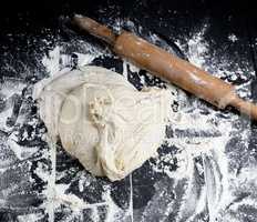 white wheat flour dough and wooden rolling pin