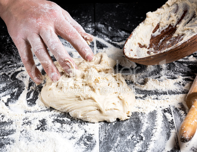 man's hands knead white wheat flour dough