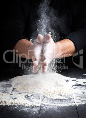 man's hands and splash of white wheat flour