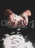 white wheat flour in male hands, black background