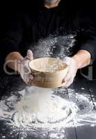 round wooden sieve with flour in male hands