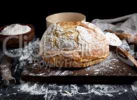 baked round white wheat bread on a brown wooden board