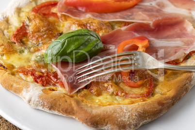 Detail einer Pizza mit Schinken und Basilikum
