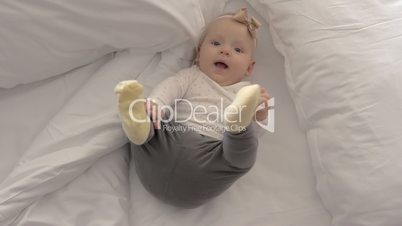 Pretty blue-eyed baby girl with bow on bed