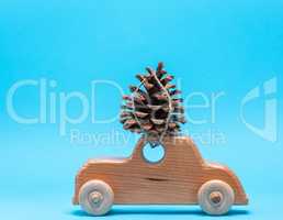wooden toy car carries on top a pine cone