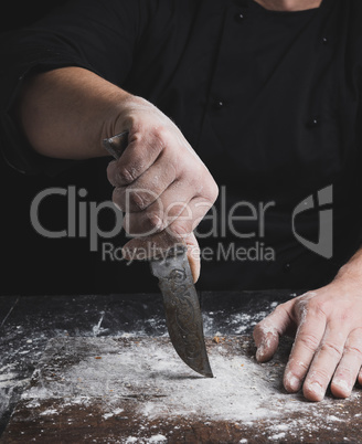 cook in black clothes holding a vintage old knife