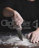 cook in black clothes holding a vintage old knife